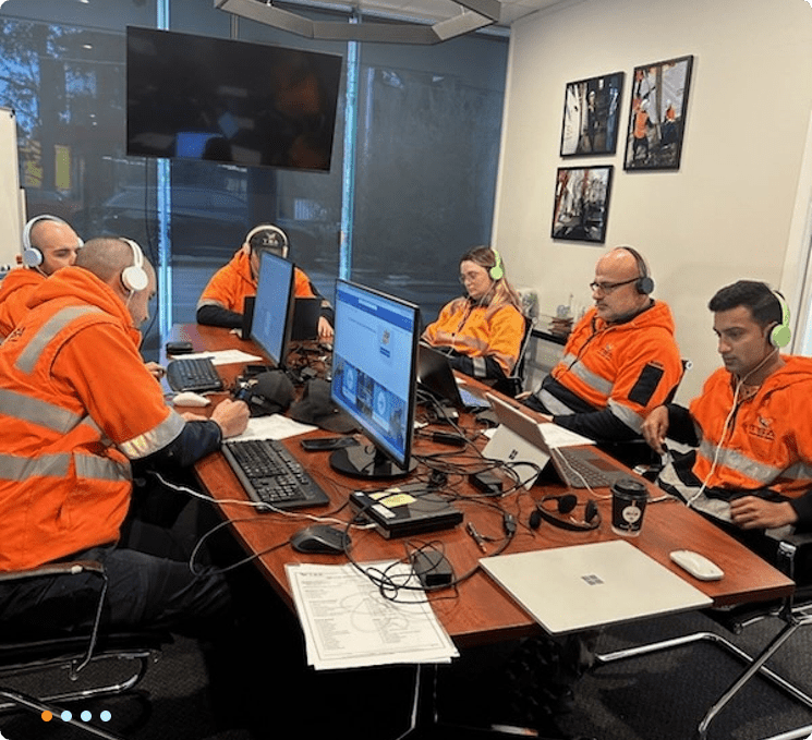 People in orange vests at computers